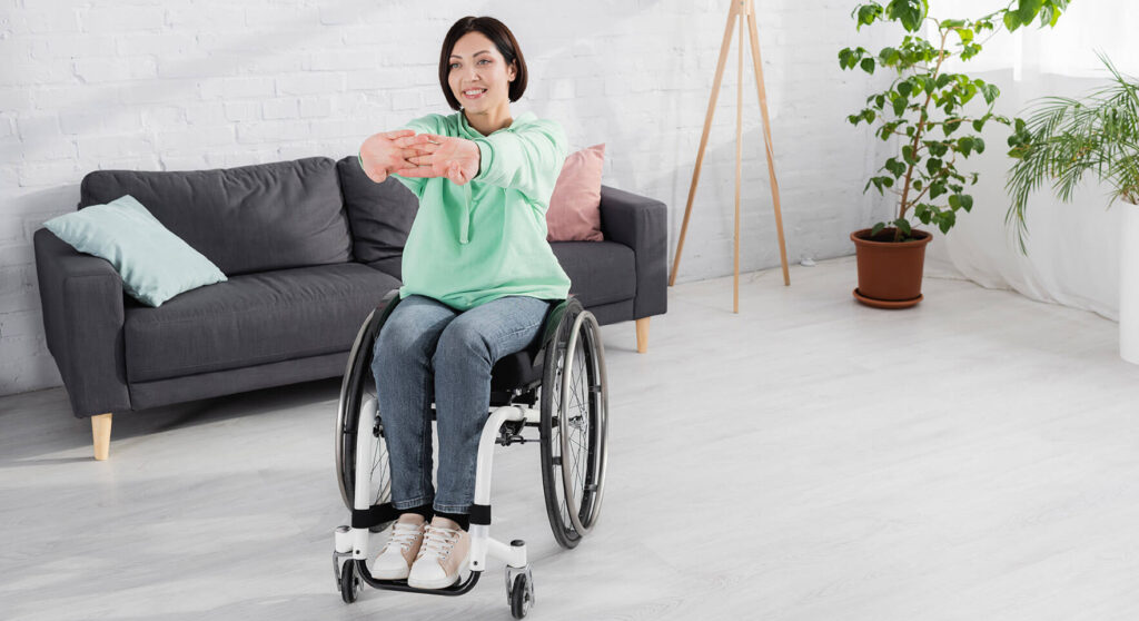 Woman in wheelchair stretching her arms out, doing adaptive yoga